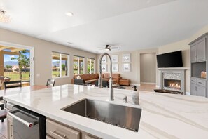 A modern kitchen with a large island, built-in oven, and a fireplace. - The Royal Fairway | 5BR/4BA Pool, Spa & Golf Views (Indio)