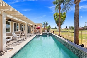 A swimming pool with a pergola, lounge chairs, and palm trees. - The Royal Fairway | 5BR/4BA Pool, Spa & Golf Views (Indio)