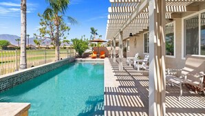 A pool area with a clear blue pool, lounge chairs, and a pergola structure. - The Royal Fairway | 5BR/4BA Pool, Spa & Golf Views (Indio)
