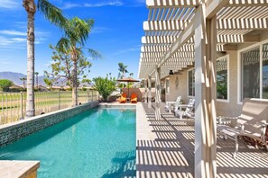 Ein Poolbereich mit klarem, blauem Pool, Liegestühlen und einer Pergola.