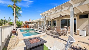 Un patio trasero con piscina, mobiliario exterior y un pérgola.