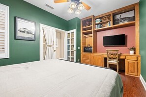 Ein Schlafzimmer mit einem Bett, einem Schreibtisch, einem Sessel, einem Fernseher und einem Bücherregal.