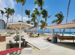 Eine Terrasse am Strand mit Sitzgelegenheiten im Freien, Palmen und Blick auf das Meer.