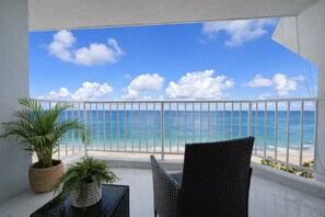 Ein Balkon mit Blick auf das Meer, ein Korbstuhl und Kübelpflanzen.