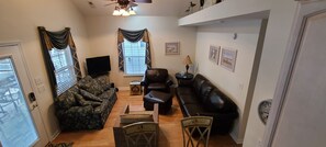 A living room with a sofa, a chair, a coffee table, a television, and a clock on the wall. - Fun In The Sun ~ Ocean Lakes 3-Bedroom 2-Bath (Myrtle Beach)
