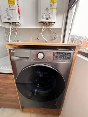 Eine kompakte LG ThinQ Waschmaschine mit Frontlader und digitaler Bedienkonsole, in einem Holzschrank platziert.
