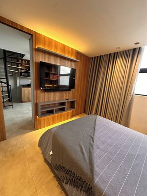A modern bedroom with a bed, a TV mounted on the wall, and a built-in shelving unit. - Luxury PH Whirlpool Tub AC Fast Wifi (Medellín)