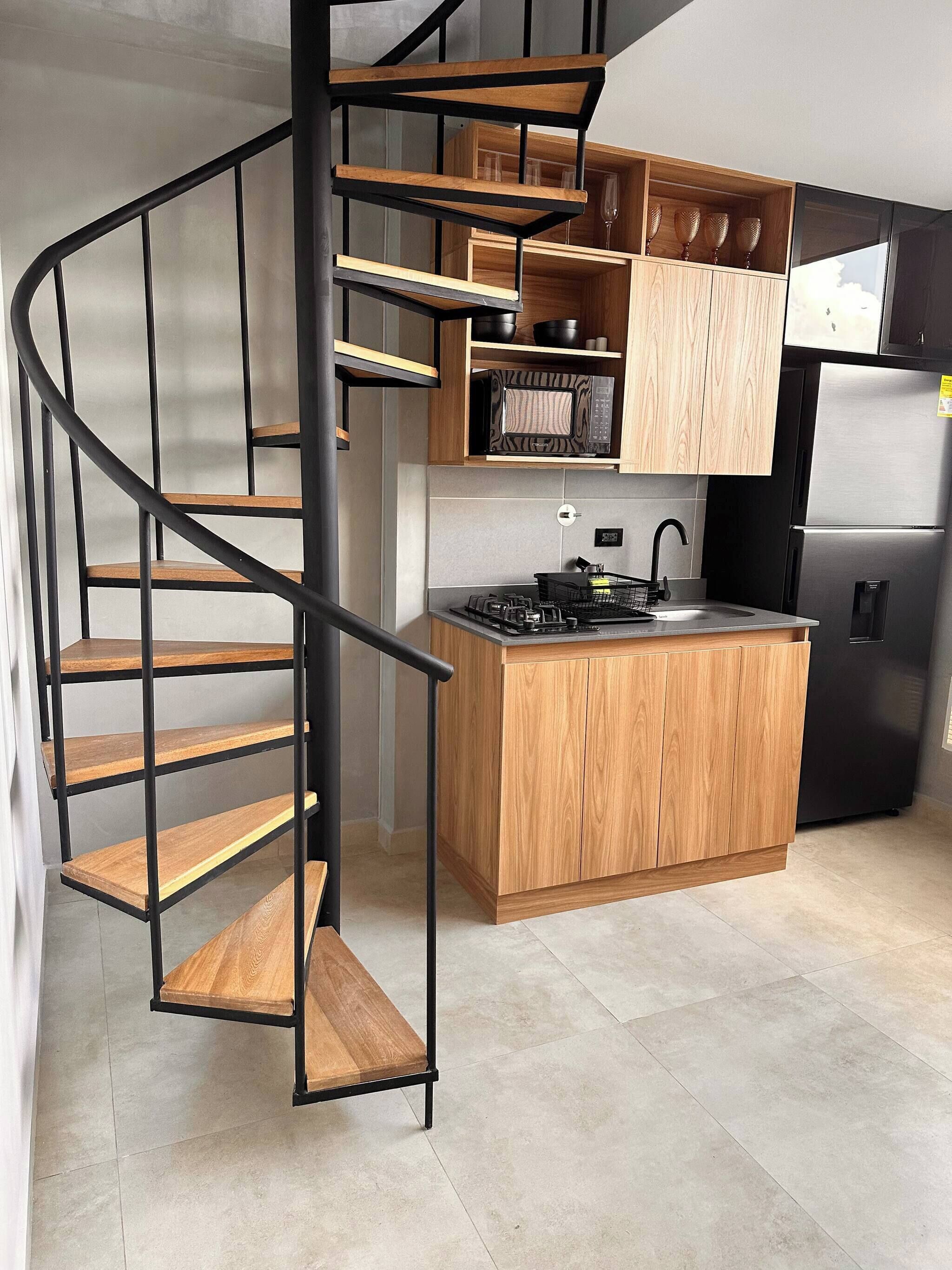 A modern kitchen with a central island, a built-in microwave, and a stainless steel refrigerator.