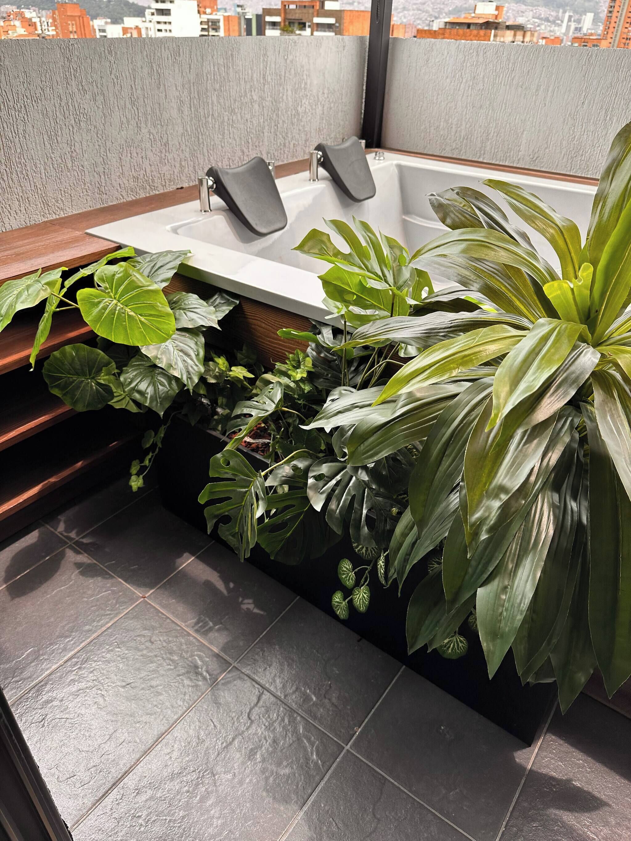 A modern bathroom with a bathtub, a sink, and a large potted plant.