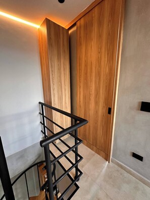 Ein modernes Interieur mit einem Holzschrank, einem schwarzen Metallregal und einem Fliesenboden.