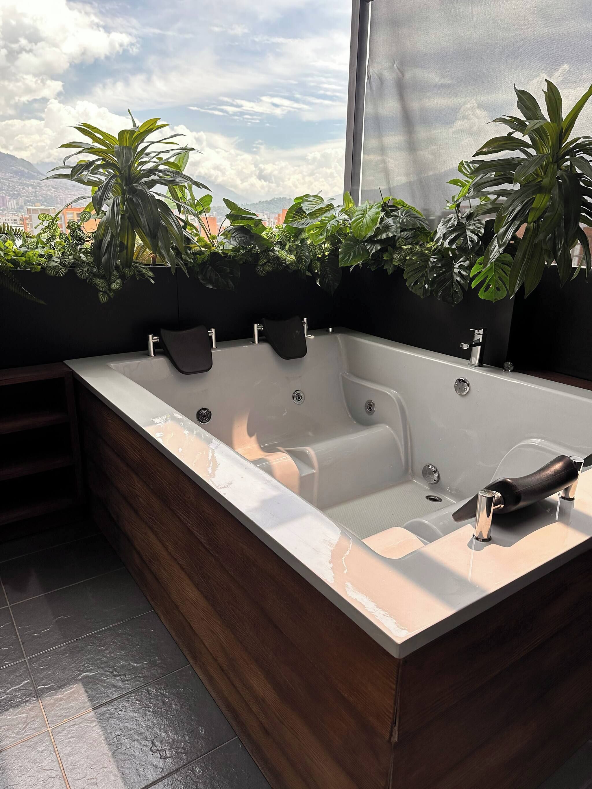 Une salle de bain moderne avec une grande baignoire, un plancher en bois et une vue sur la ville grâce à une grande fenêtre.