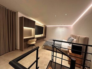 Ein modernes Schlafzimmer mit Bett, Schreibtisch und Fernseher.