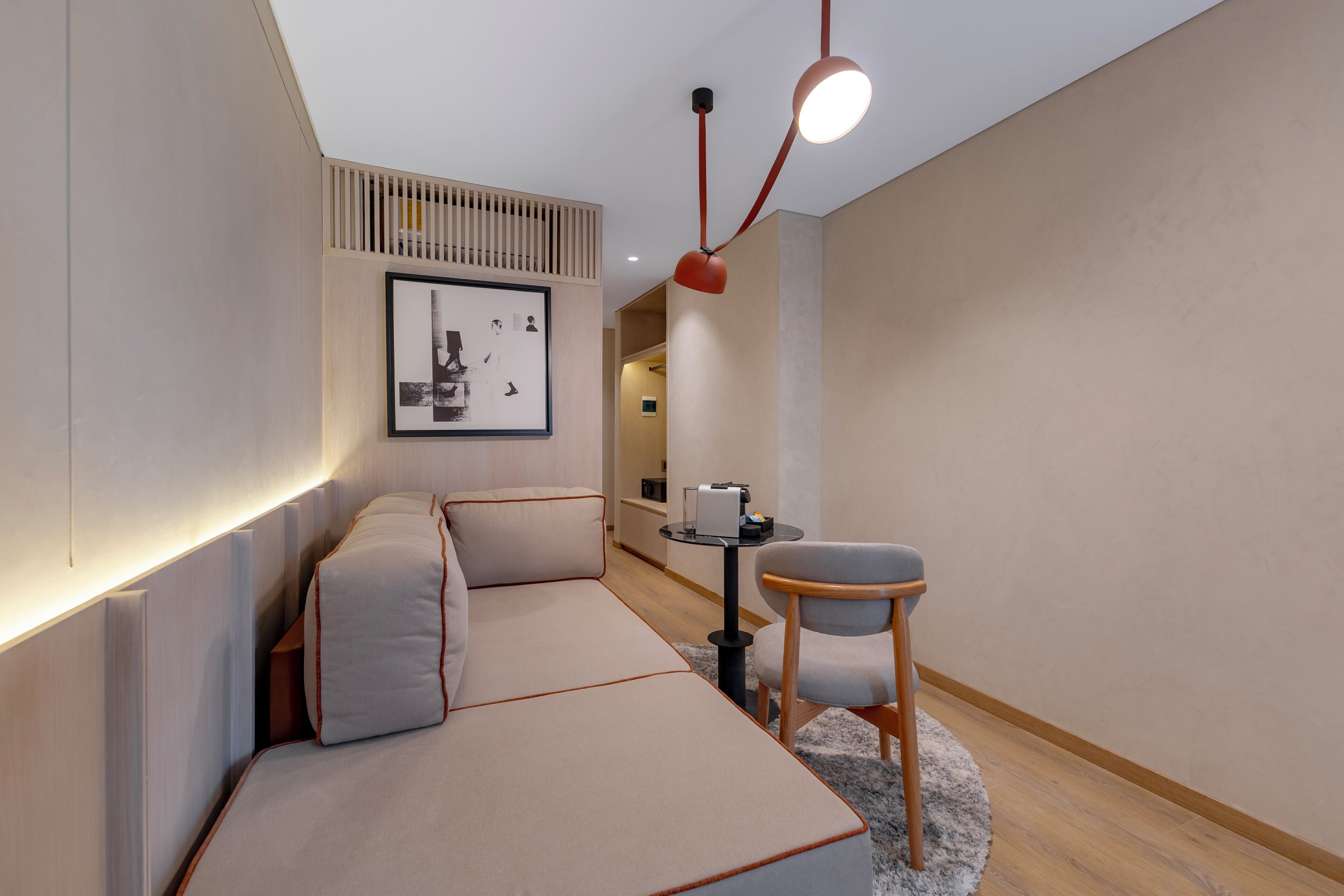 Een moderne kamer met een bank, een stoel, een tafeltje en een foto aan de muur.
