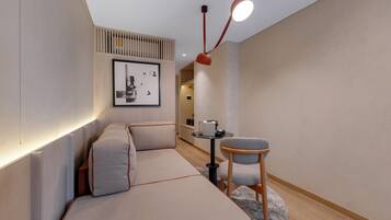 Een moderne kamer met een bank, een stoel, een tafeltje en een foto aan de muur.