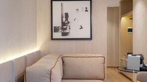 Ein modernes Zimmer mit Schlafsofa, gerahmtem Kunstwerk und Pendelleuchte.