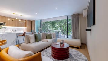 Un salon moderne comprenant un canapé, des fauteuils, une table basse et un coin cuisine avec une table à manger et des chaises.