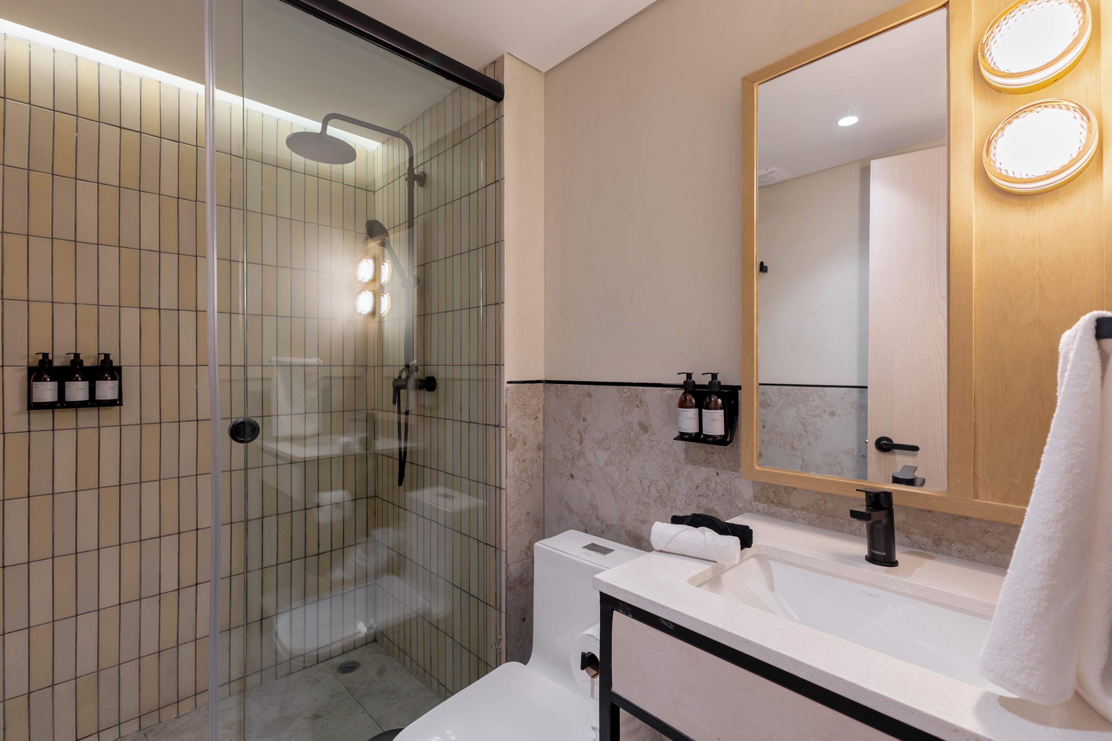 A modern bathroom with a glass-enclosed shower, a white sink, and a mirror with lights.