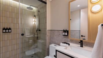A modern bathroom with a glass-enclosed shower, a white sink, and a mirror with lights.
