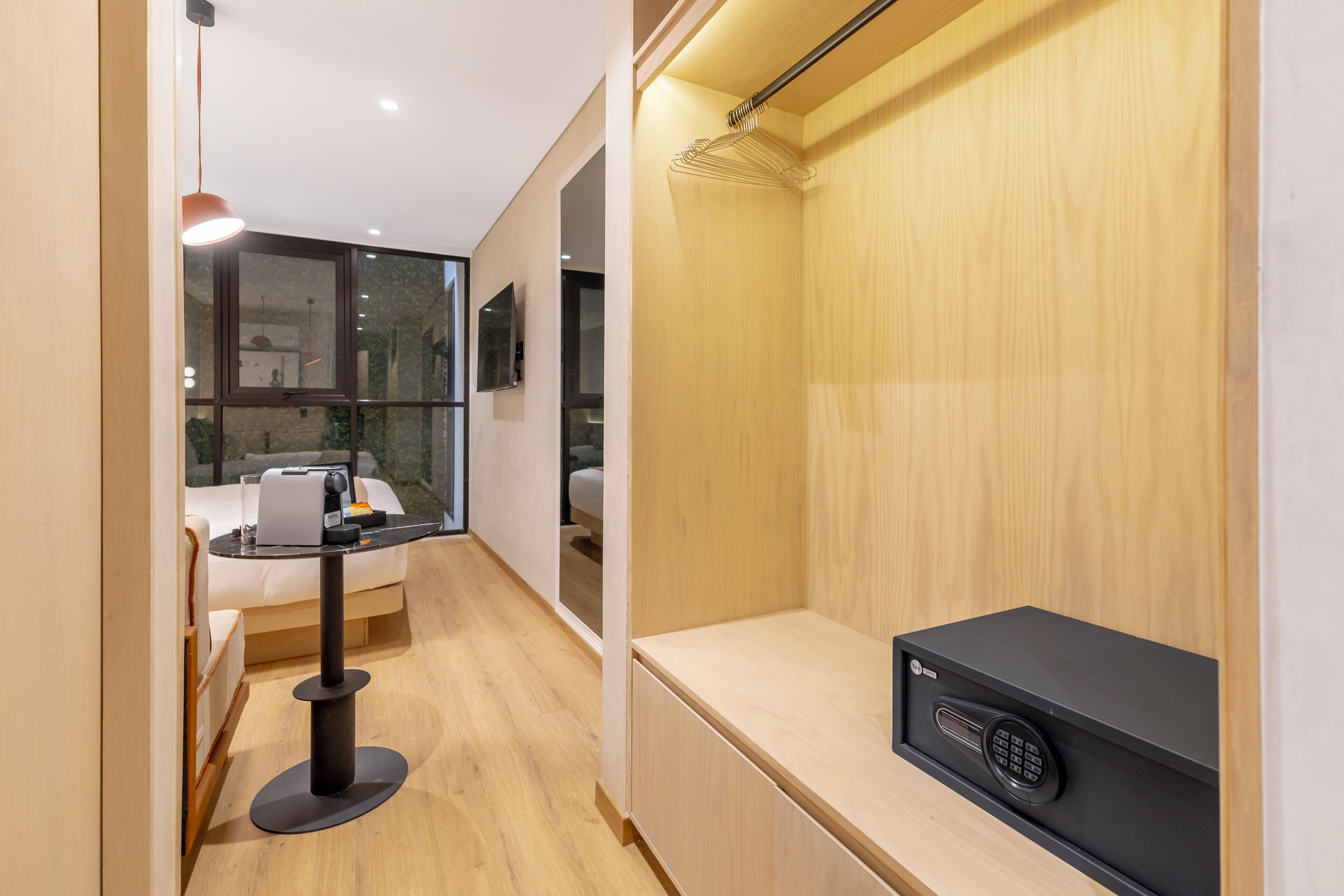 A modern hotel room with a bed, a desk, a coffee machine, and a TV.