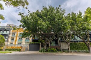 Un edificio moderno con varios pisos, amplias ventanas y un árbol en primer plano.