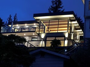 Ein modernes Haus mit Glasbalkon, einer Treppe und einem gut beleuchteten Innenraum.