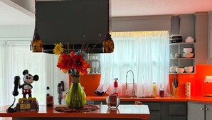 Et moderne køkken med en central ø, barstole, en Mickey Mouse-telefon og en vase med blomster.