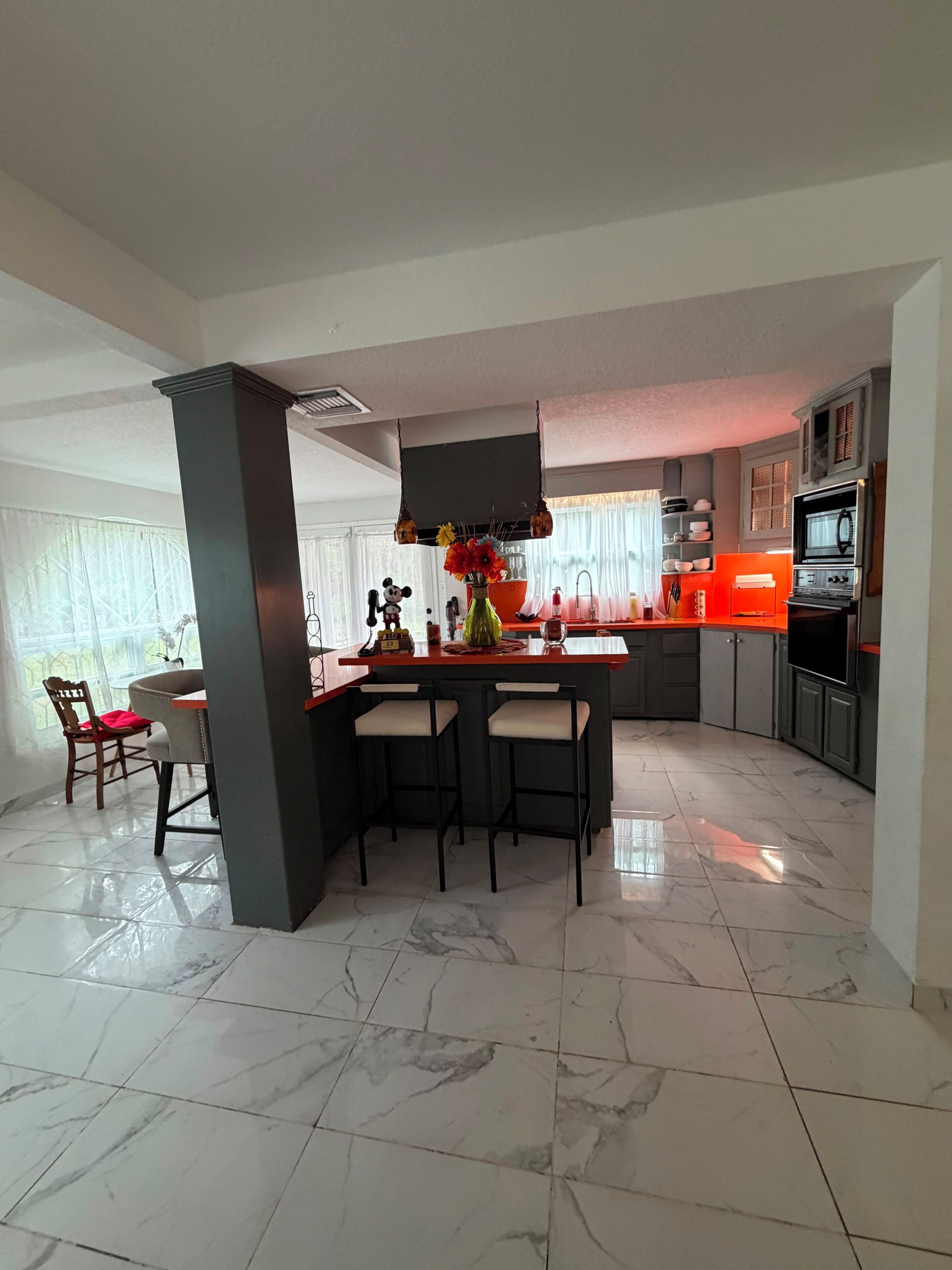 A modern kitchen with a central island, bar stools, and a built-in oven.