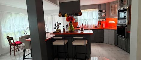 A modern kitchen with a central island, bar stools, and a built-in oven.