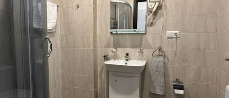 A modern bathroom with a glass shower enclosure, a sink with a mirror above, and a toilet.