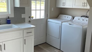 Una sala de lavandería con dos lavadoras, un lavabo y armarios.