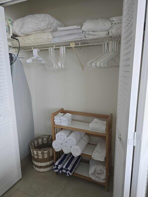 A storage area with shelves and hangers for towels and a wicker basket. - Cozy Beachside condo in superb Fort Myers Beach (Fort Myers Beach)