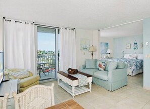 Ein Wohnzimmer mit einer Couch, einem Couchtisch, einem Korbstuhl und einem Balkon mit Aussicht.