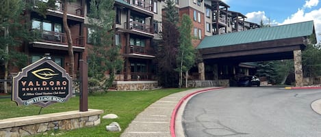 Un hotel de varios pisos con un letrero que indica Valdora Mountain Lodge, un resort Hilton Grand Vacations Club, y una entrada cubierta.