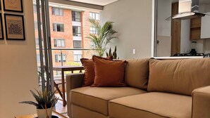A modern living room with a beige sofa, a wooden coffee table, and a potted plant. - Premium Village 24 7 Security Balcony Fast Wifi (Medellín)