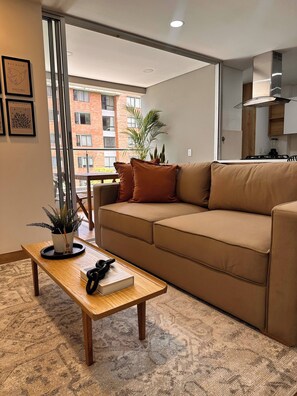 A modern living room with a beige sofa, a wooden coffee table, and a potted plant. - Premium Village 24 7 Security Balcony Fast Wifi (Medellín)