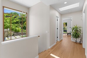 Ein modernes Interieur mit Holzboden, Blick ins Grüne und einer Tür zu einem weiteren Raum.