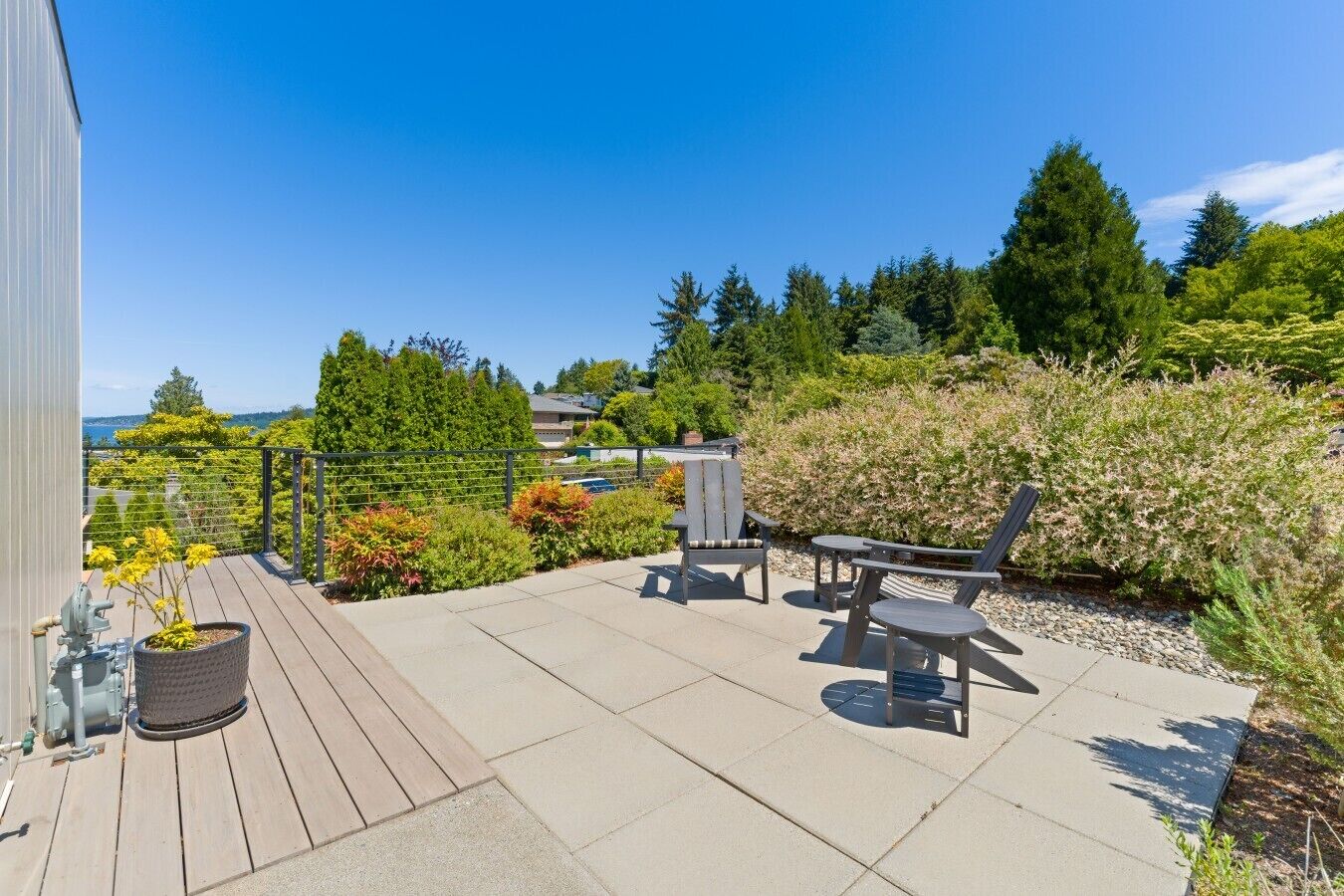A patio with outdoor furniture, a potted plant, and a view of a forested area.
