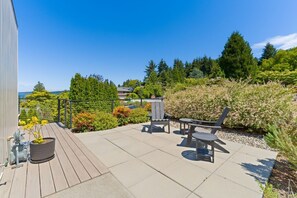 A patio with outdoor furniture, a potted plant, and a view of a forested area.