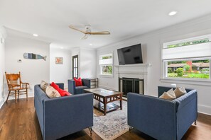 A modern living room with a fireplace, two sofas, a coffee table, and a television. - Nice 3-bedroom house in Wilmington perfect for your getaway (Wilmington)