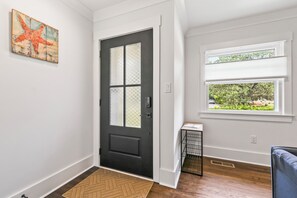 A room with a black door, a window with blinds, a small table, and a rug. - Nice 3-bedroom house in Wilmington perfect for your getaway (Wilmington)