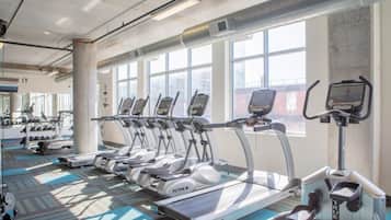 Ein Fitnessstudio mit mehreren Laufbändern, Kraftgeräten und Kurzhanteln.