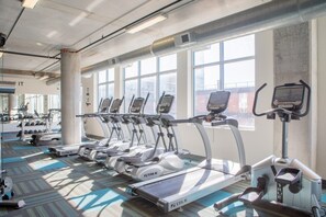 Une salle de sport équipée de plusieurs tapis de course, de machines de musculation et d’haltères.