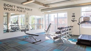 A gym with exercise equipment, large windows, and motivational wall text. - Luxury Penthouse Apt Near Brady St with Balcony and Lake View (Milwaukee)