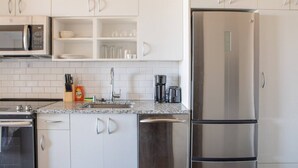 A modern kitchen with white cabinets, a stainless steel refrigerator, a microwave, and a coffee maker. - Luxury Penthouse Apt Near Brady St with Balcony and Lake View (Milwaukee)