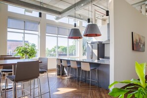 A modern kitchen with a bar area, large windows, and a plant. - Luxury Penthouse Apt Near Brady St with Balcony and Lake View (Milwaukee)
