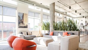 Ein großzügiger Lounge-Bereich mit moderner Möblierung, großen Fenstern und Zimmerpflanzen.