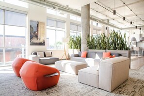 A spacious lounge area with modern furniture, large windows, and indoor plants. - Luxury Penthouse Apt Near Brady St with Balcony and Lake View (Milwaukee)