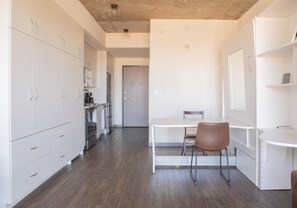 A modern kitchen with white cabinets, a dining table with chairs, and a visible door leading to another room. - Luxury Penthouse Apt Near Brady St with Balcony and Lake View (Milwaukee)