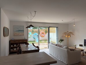 A modern living room with a dining area, a sofa, a coffee table, and a TV. - Ti kaz Charming 3-bedroom house in Arzon idéale située entre le port/bourg/plage (Arzon)