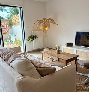 Ein modernes Wohnzimmer mit einer Couch, einem Holztisch, einem Fernseher und einem großen Fenster.